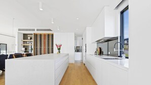 Eine moderne Küche mit Kochinsel, integriertem Weinschrank und großem Fenster.