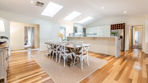A modern kitchen with white cabinets, a central island, and a built-in oven. - Hamptons Inspired Luxury (Mount Martha)