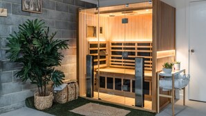 A modern sauna with glass doors, wooden benches, and a small table with towels. - Hamptons Inspired Luxury (Mount Martha)