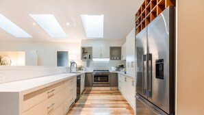A modern kitchen with a central island, built-in appliances, and skylights. - Hamptons Inspired Luxury (Mount Martha)