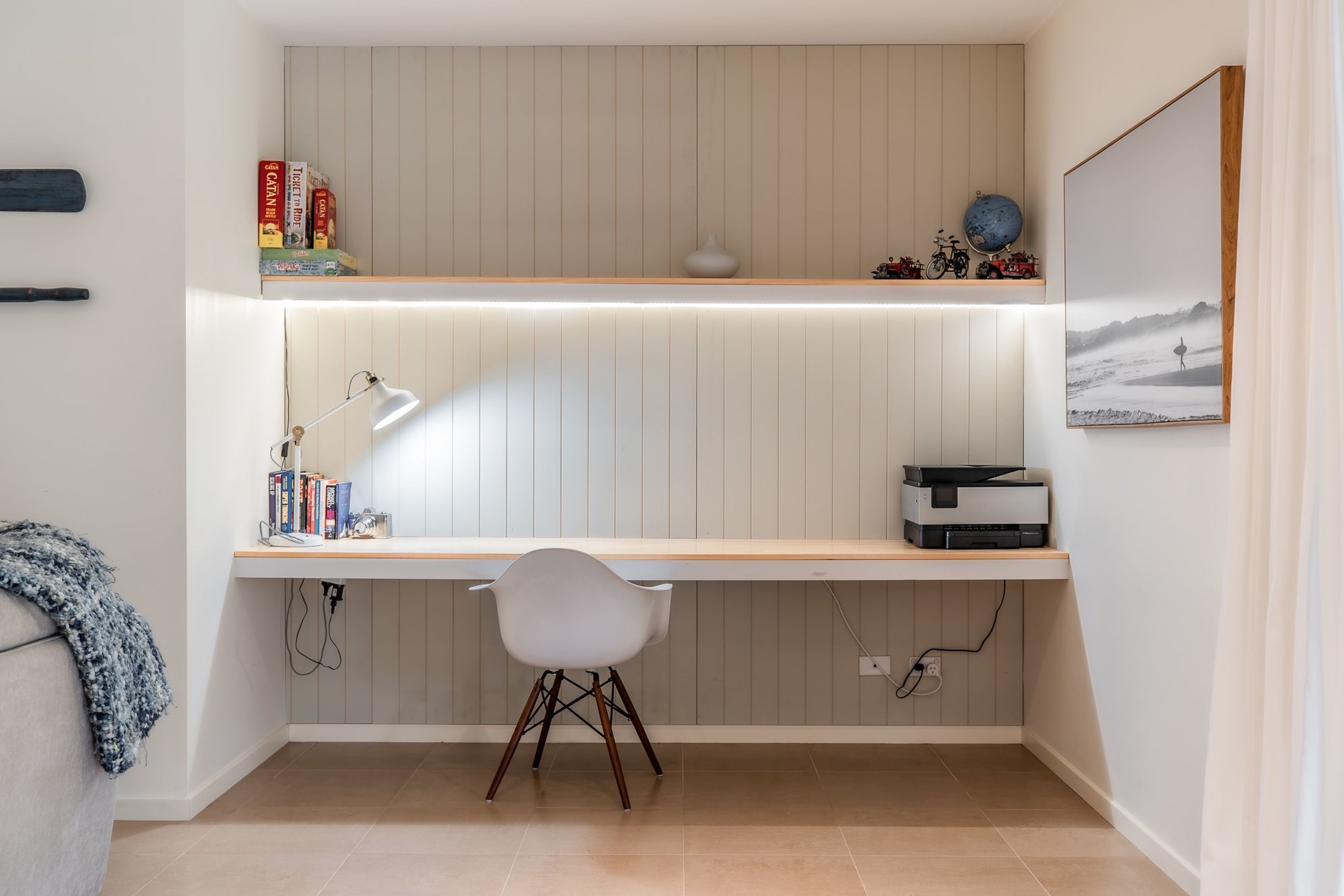 Un espace de travail compact comprenant un bureau, une chaise et une étagère remplie de livres et surmontée d’un globe terrestre.