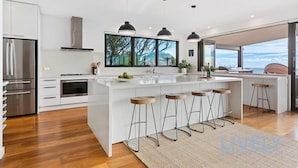 A modern kitchen with a large island, bar stools, and a view of the outdoors.