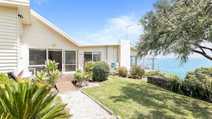 Una casa costera con un patio, vistas al mar y varias plantas.
