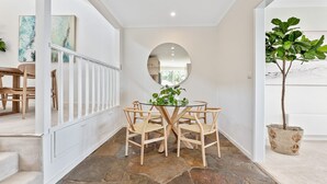 Un comedor con una mesa redonda y sillas, un espejo en la pared y una planta en maceta.