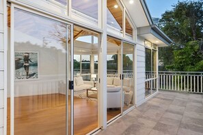 A modern house with a glass-enclosed porch, wooden flooring, and a white railing. - Blairgowrie Beachside Retreat Solar Heated Pool (Blairgowrie)