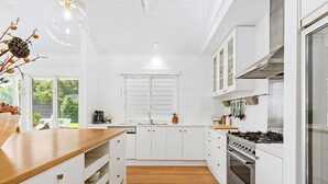 Eine moderne Küche mit weißen Schränken, einer Holz Arbeitsplatte, einem Gasherd und einem Fenster mit Blick auf Grünflächen.