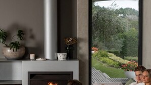A modern living room with a fireplace, comfortable seating, and a large window overlooking a garden. - Luxury Portsea Sanctuary Gas Heat Pool Gardens (Portsea)
