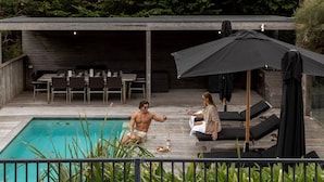 A poolside area with a wooden deck, lounge chairs, and a covered seating area. - Luxury Portsea Sanctuary Gas Heat Pool Gardens (Portsea)