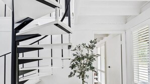 A modern interior with a spiral staircase, a potted plant, and a view through a door. - The Coast Country Cottage (Balnarring Beach)