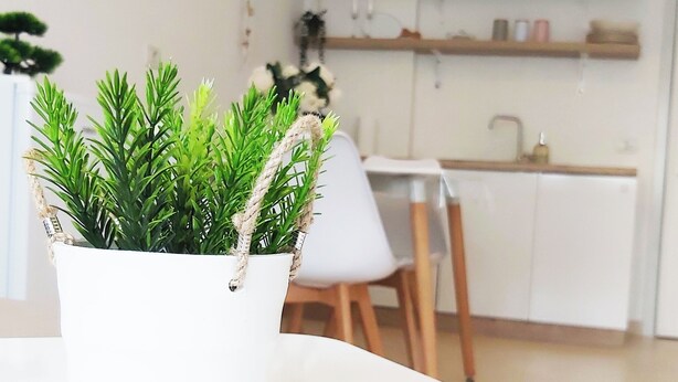 Una cocina moderna con armarios blancos, estantes de madera y una lámpara colgante.