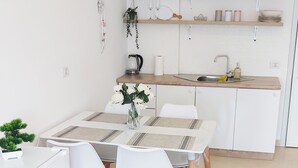 Una cocina moderna con armarios blancos, encimera de madera y una lámpara colgante.
