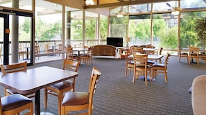 Dine and relax in a spacious area with large windows, comfortable seating, and a TV for entertainment.
