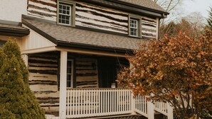 A two-story wooden house with a front porch and a small balcony.