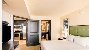 A hotel room with a bed, a television, a kitchenette, and a bathroom. - Virginia Beach | Oceanfront Coastal Stay | Pool & Beach | 2BR (Virginia Beach)