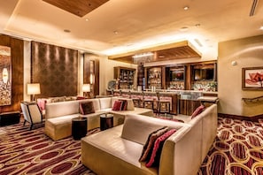 Een hotel lobby met een bar, zitgedeeltes en een kamerbreed tapijt.