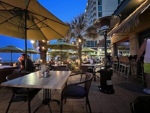 An outdoor dining area with tables and chairs, umbrellas, and a decorative lamp post.