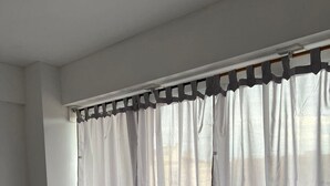 Una habitación de hotel con una cama grande, ropa de cama a rayas y cortinas translúcidas.