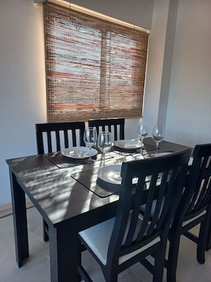 A dining table with chairs, plates, and wine glasses set for four. - Departamento en el centro de Mendoza  (Mendoza)