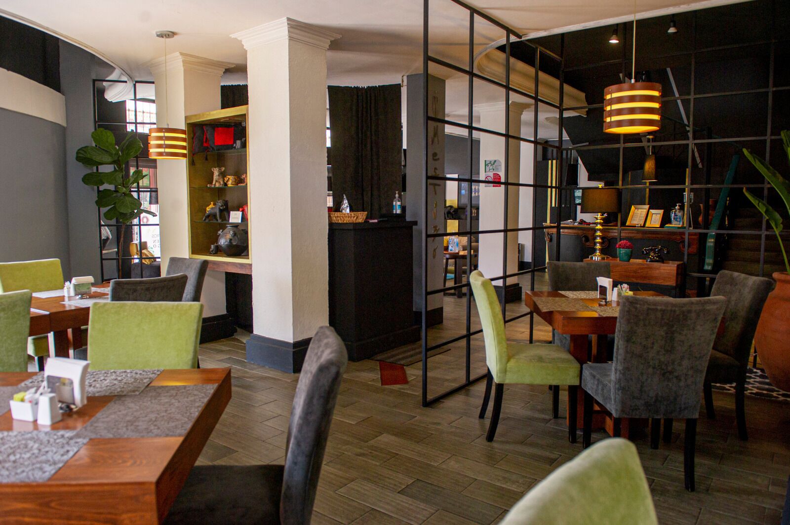 Un restaurante con mesas y sillas de madera, una zona de bar y una planta grande.