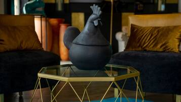 Una sala de estar moderna con una mesa de centro de vidrio, sofás oscuros y jarrones decorativos.