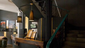 Una escalera con barandilla de madera y pared negra con pasamanos de metal.