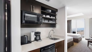 A compact hotel kitchenette with a microwave, coffee maker, and sink.