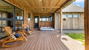 A wooden deck with rocking chairs and a hot tub.