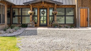 A modern building with a wooden facade, large windows, and a gravel driveway.