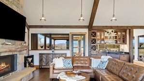 A spacious living area with a fireplace, leather sofas, and a kitchen in the background.