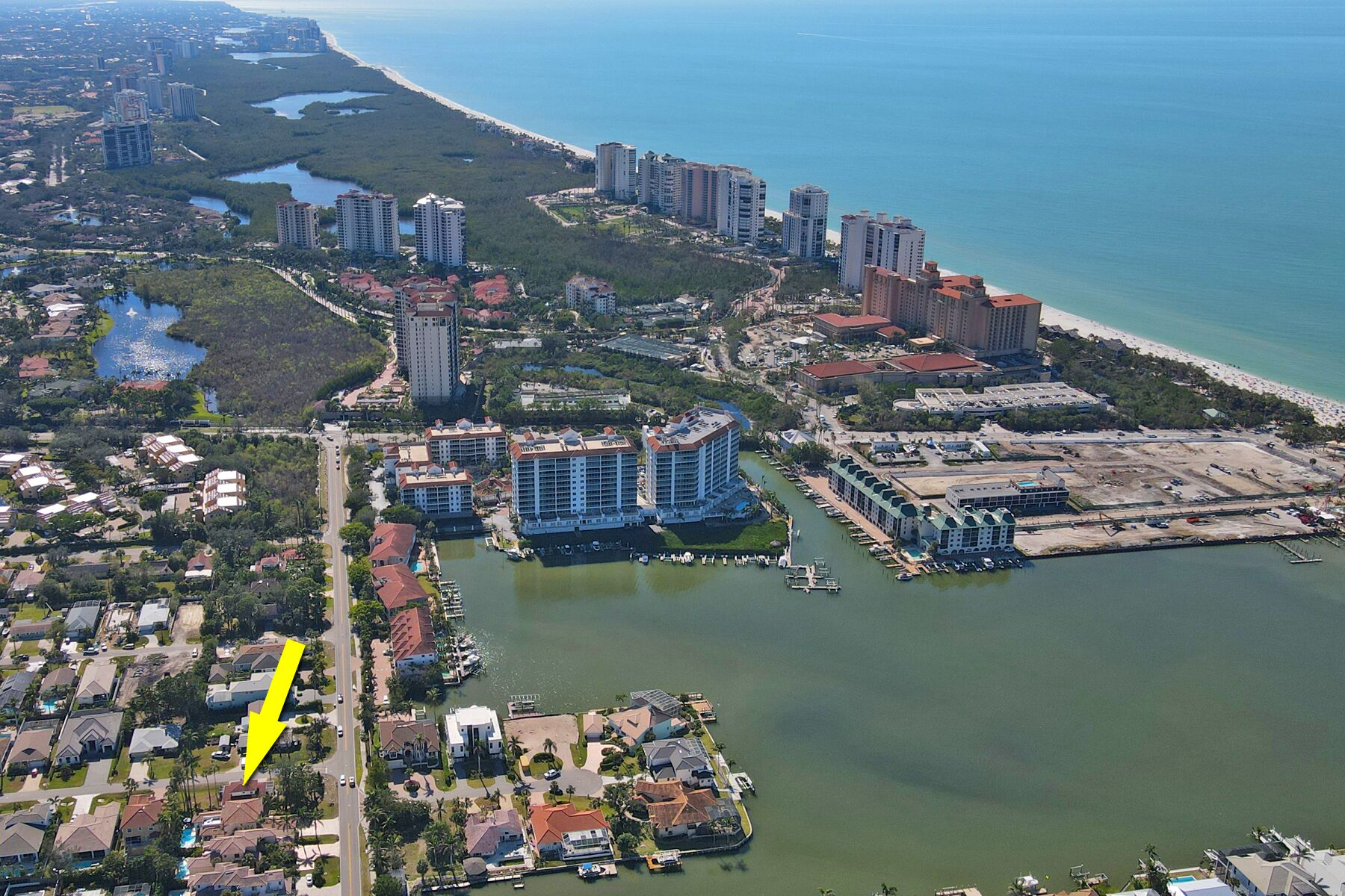 Vista aérea de una zona costera con edificios altos, un puerto deportivo y áreas residenciales.