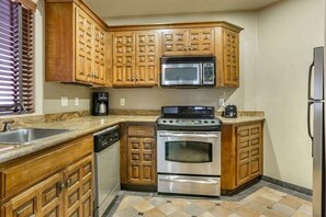 Kitchen equipped with a gas stove, microwave, and dishwasher, featuring a granite countertop and tiled backsplash.
