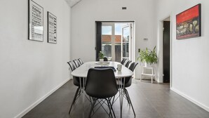 Et moderne spiseområde med et rundt bord, sorte stole og udsigt til det frie gennem en glasdør.