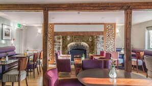 A restaurant with a stone fireplace, wooden beams, and purple seating. - Devon | Peaceful Country Escape | Pool + Sauna (Devon)