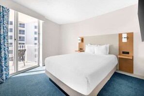 A hotel room with a large bed, a balcony with a chair, and a view of buildings.