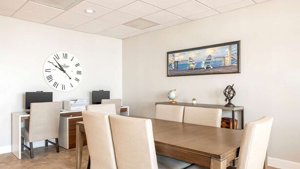 Una sala conferenze moderna con un orologio grande, un tavolo da pranzo con sedie e un quadro appeso al muro.
