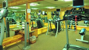 Ein Fitnessstudio mit verschiedenen Trainingsgeräten, Spiegeln und einem digitalen Bildschirm.