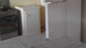 Eine Küche mit Herd, Kühlschrank und einem kleinen Schrank.