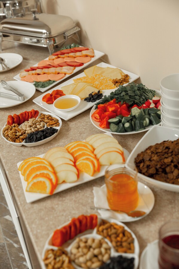A buffet table with various food items including fruits, vegetables, and nuts.