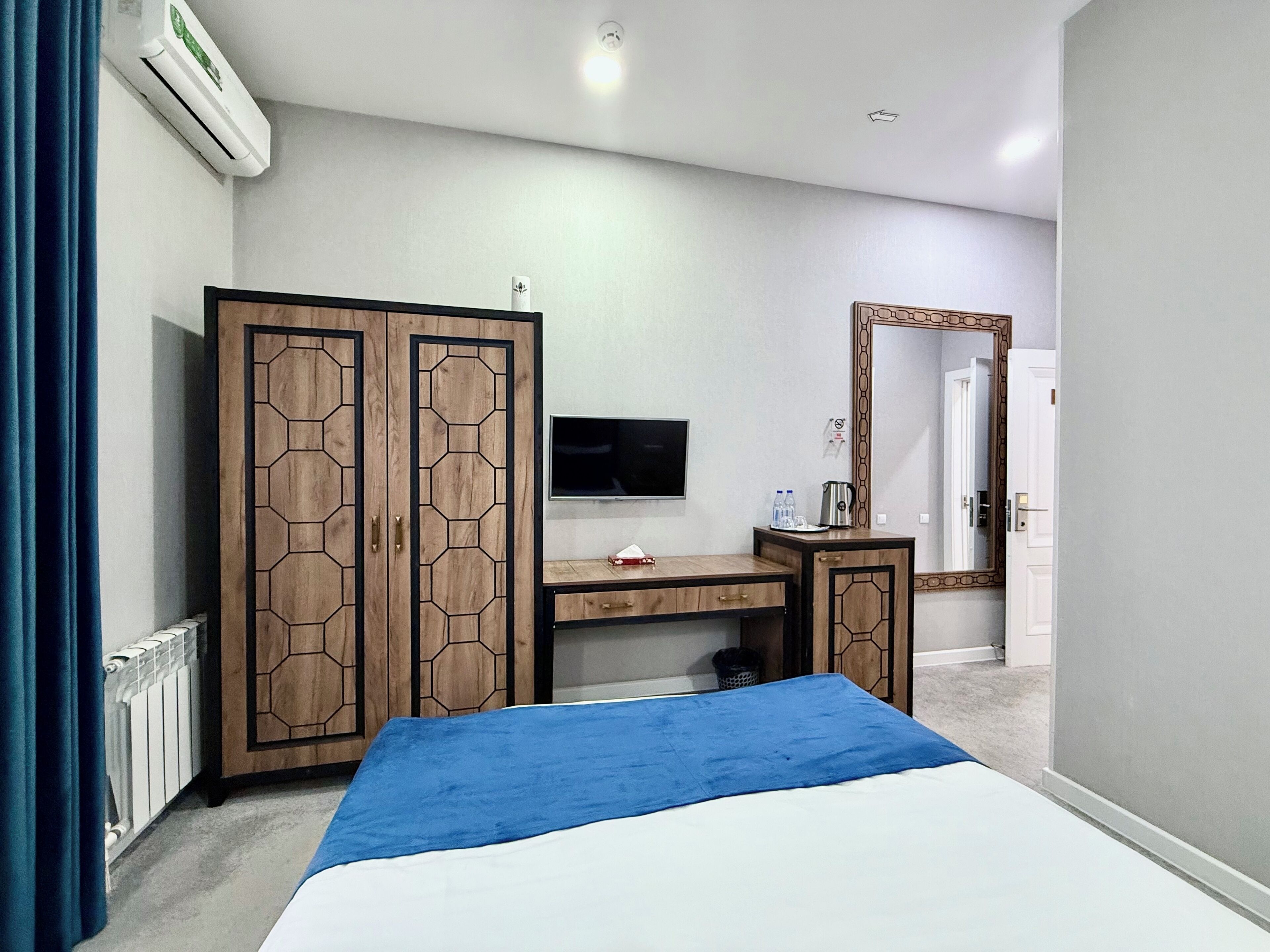 Ein Schlafzimmer mit Bett, Fernseher, Kleiderschrank, Schreibtisch und Spiegel.