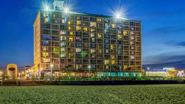 Un hôtel à plusieurs étages au design moderne, doté d’un beffroi imposant et de nombreuses fenêtres illuminées.