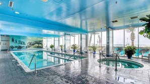 Une piscine intérieure à l’eau claire, avec un sol carrelé et des chaises longues.