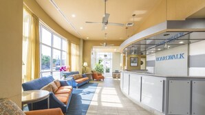 Un hall d’hôtel comprenant des espaces aménagés avec des sièges, un comptoir d’accueil et une enseigne indiquant « BOARDWALK ».