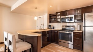 Una cocina moderna con una isla central, electrodomésticos de acero inoxidable y armarios de madera oscura.