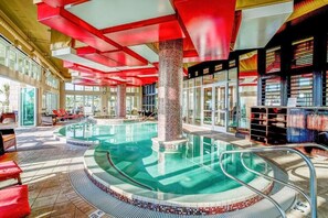 A swimming pool with a tiled deck, a central column, and a glass enclosure.