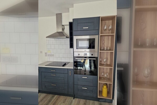 A kitchen with a built-in microwave, oven, and a wooden wine rack.