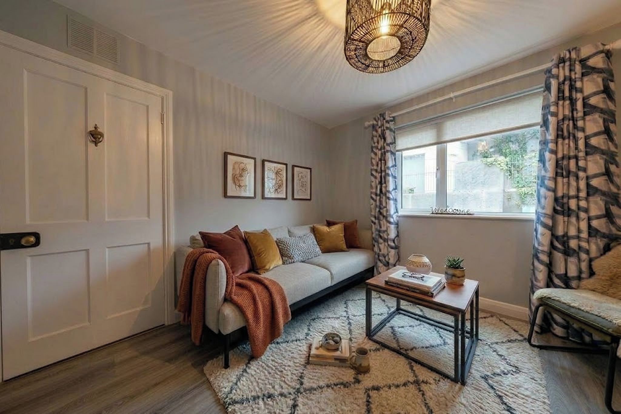 A cozy living room with a sofa, a coffee table, and a window with curtains.