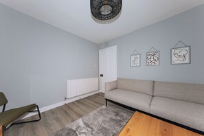 Una sala de estar moderna con un sofá gris, una mesa de centro de madera y una alfombra estampada.
