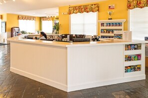 A reception area with a counter, a coffee machine, and a bookshelf with magazines. - Orlando | Family Lake Retreat | Pool + Hot Tub | 2BR Condo (Orlando)