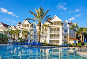 A hotel with a swimming pool, palm trees, and a clear blue sky. - Orlando | Family Lake Retreat | Pool + Hot Tub | 2BR Condo (Orlando)
