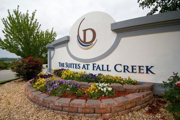 Une enseigne pour « The Suites at Fall Creek », avec un logo et un espace paysager agrémenté de fleurs.